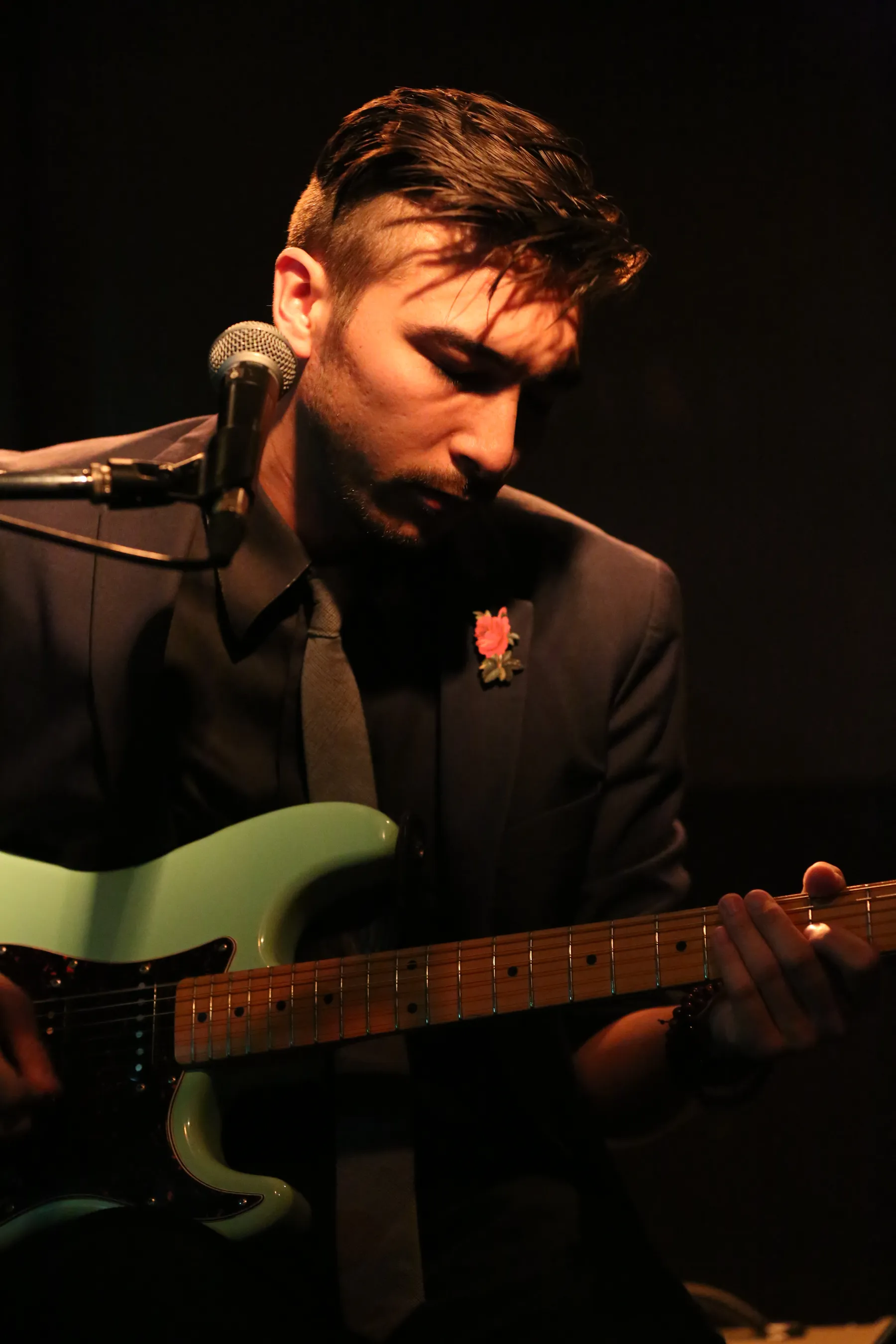 Alex Nishi in close focus, fingers on the fretboard mid-song